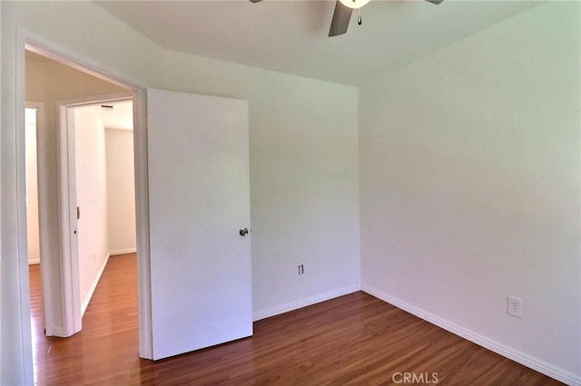 unfurnished room with wood finished floors, a ceiling fan, and baseboards