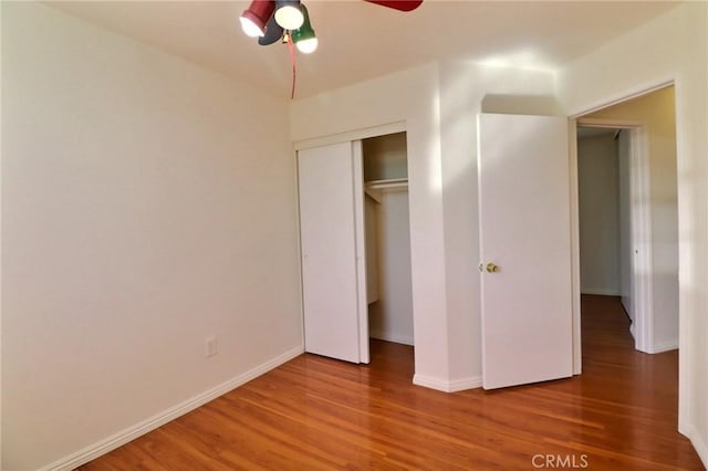 unfurnished bedroom with a closet, ceiling fan, baseboards, and wood finished floors