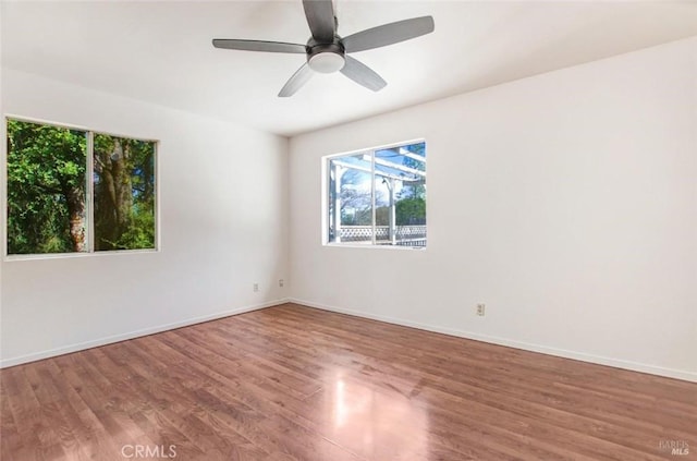 empty room featuring ceiling fan, baseboards, and wood finished floors