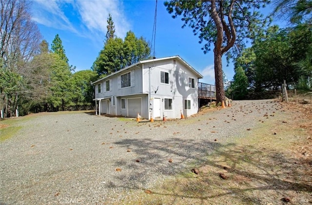 back of house featuring a garage and gravel driveway