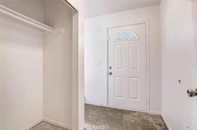 foyer entrance featuring baseboards and unfinished concrete floors