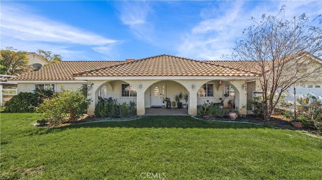 back of house featuring a lawn, a tiled roof, a chimney, and stucco siding