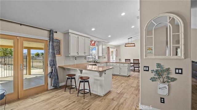 kitchen featuring a peninsula, light wood-style flooring, a wealth of natural light, and a sink