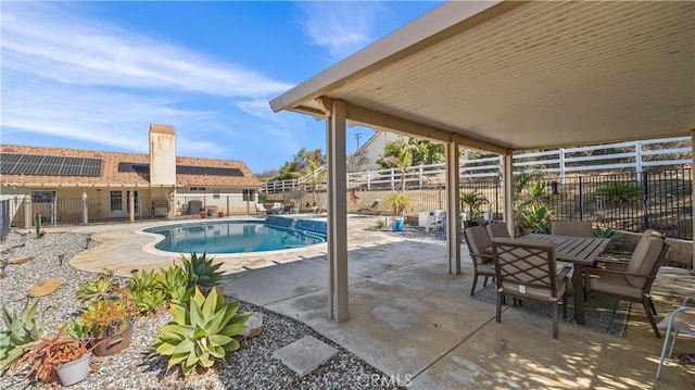 view of pool with a fenced backyard, outdoor dining space, a pool with connected hot tub, and a patio