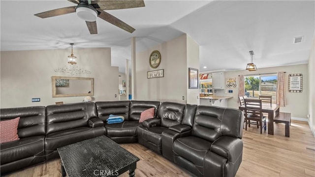 living room featuring visible vents, lofted ceiling, ceiling fan, and light wood finished floors