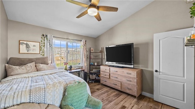 bedroom with vaulted ceiling, light wood-style floors, baseboards, and ceiling fan