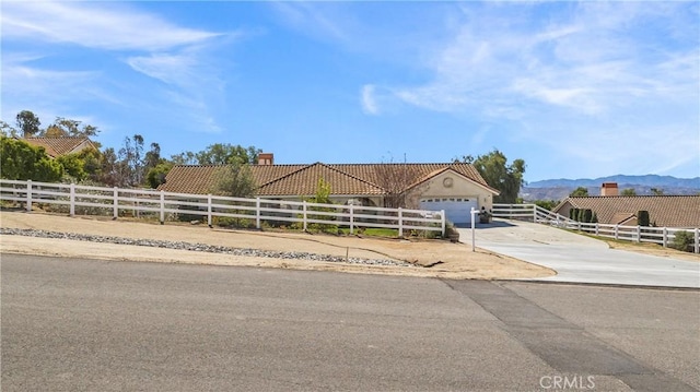 view of front of house with a fenced front yard, a garage, concrete driveway, and a mountain view