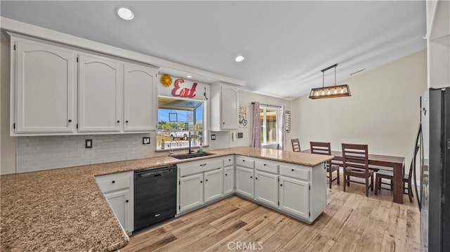 kitchen featuring dishwasher, light wood-type flooring, a peninsula, stainless steel fridge, and a sink