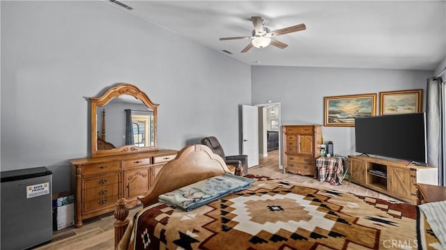 bedroom with vaulted ceiling, fridge, light wood-style floors, and visible vents