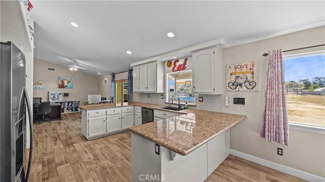 kitchen with light wood finished floors, a peninsula, a sink, vaulted ceiling, and stainless steel fridge