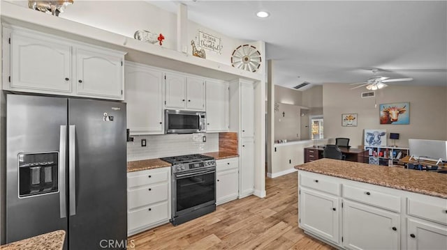 kitchen with stainless steel appliances, vaulted ceiling, and white cabinetry