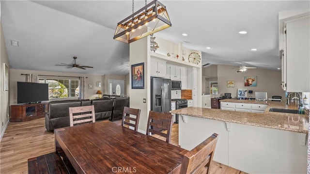 dining room with ceiling fan, light wood-style floors, and vaulted ceiling