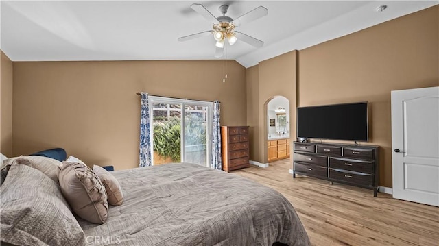 bedroom with lofted ceiling, ensuite bathroom, arched walkways, light wood finished floors, and baseboards