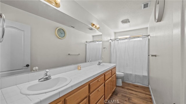 full bath featuring a textured ceiling, wood finished floors, visible vents, and a sink