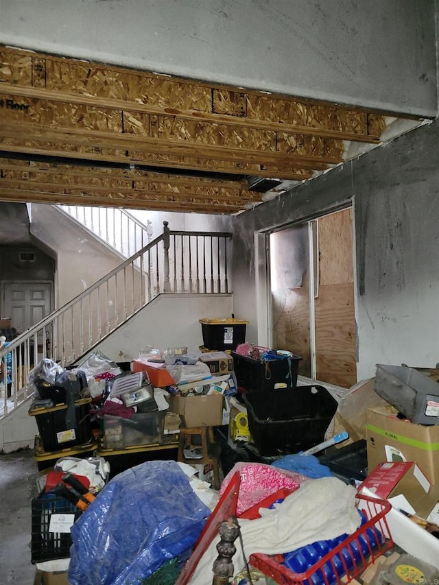 miscellaneous room with stairway and unfinished concrete flooring