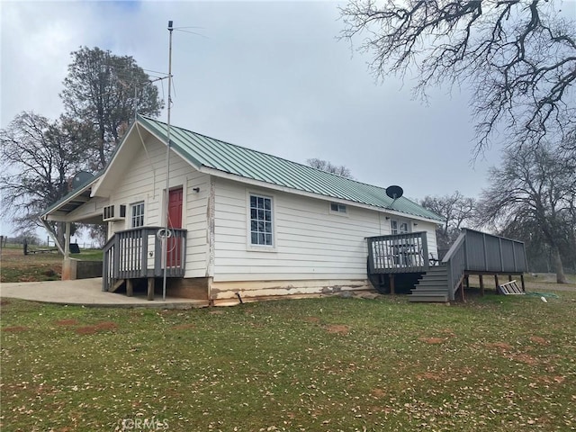 back of property featuring metal roof, a yard, and a wooden deck