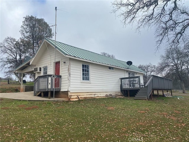 view of home's exterior featuring metal roof, a wooden deck, and a yard
