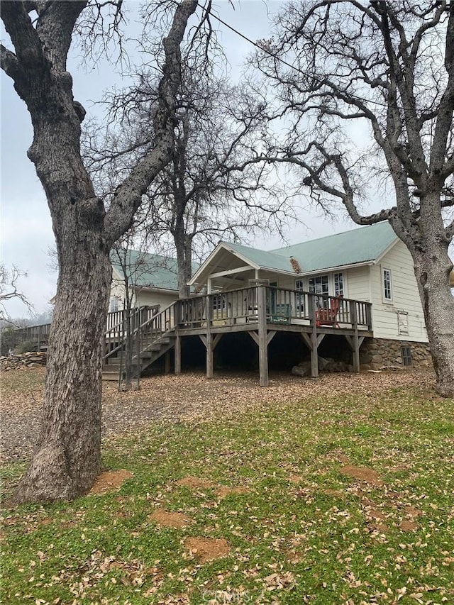 rear view of house featuring metal roof, stairway, and a wooden deck