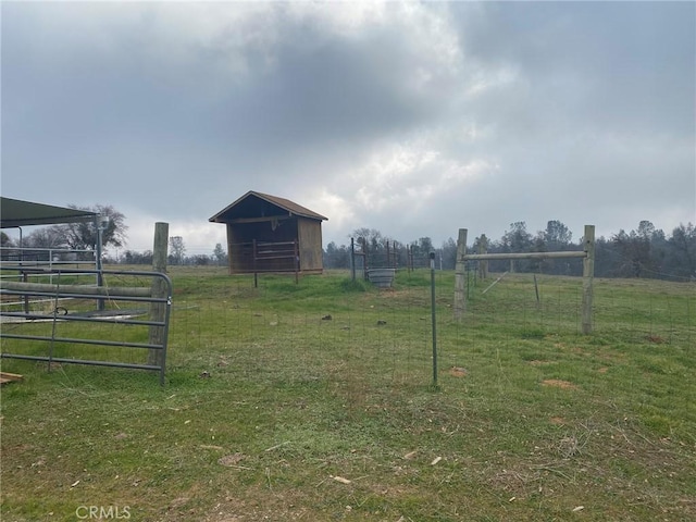 view of yard with a rural view, an outdoor structure, and fence