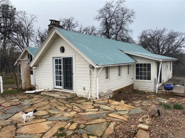 exterior space with a chimney and metal roof