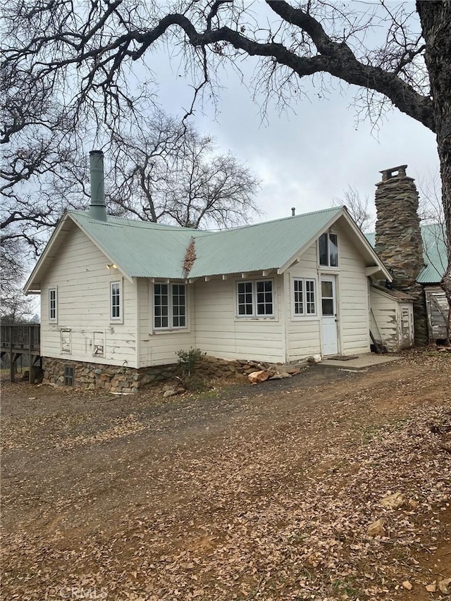 back of property featuring metal roof and a chimney