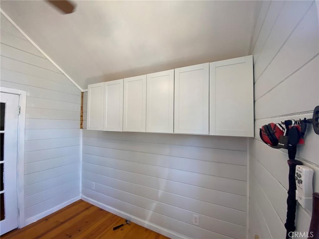 unfurnished room featuring vaulted ceiling, wood walls, and wood finished floors