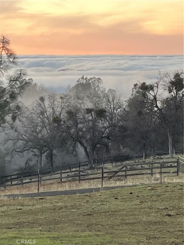 yard at dusk featuring fence and a rural view