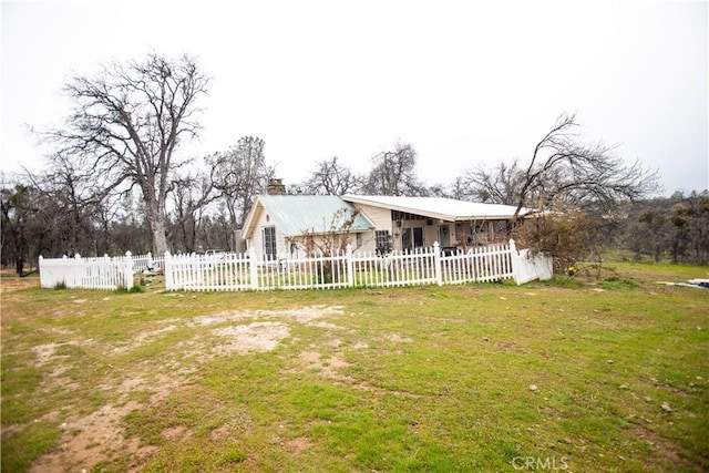 view of front facade featuring a chimney, a front yard, and fence private yard