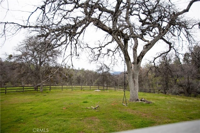 view of yard featuring a rural view, a forest view, and fence