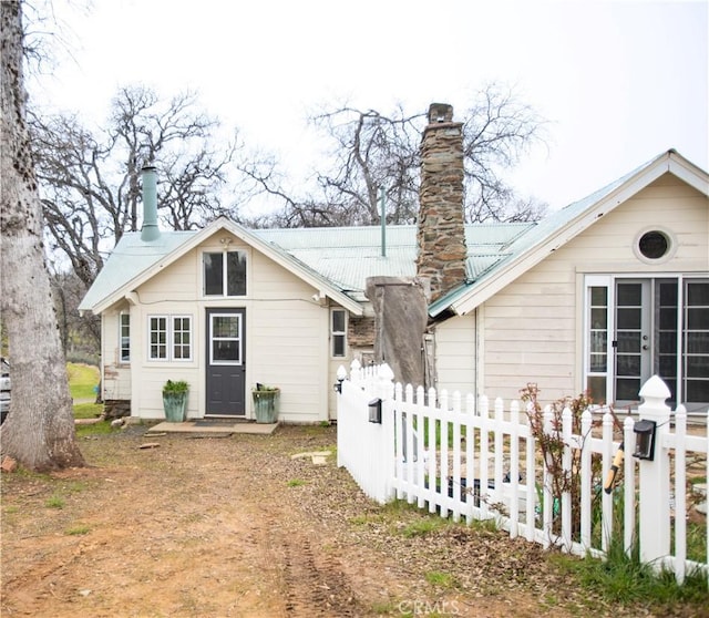 back of property featuring metal roof, fence, and a chimney