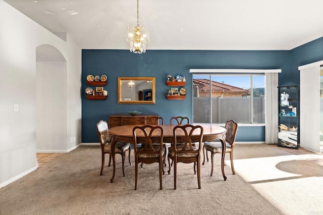 dining area with carpet floors, arched walkways, a chandelier, and baseboards