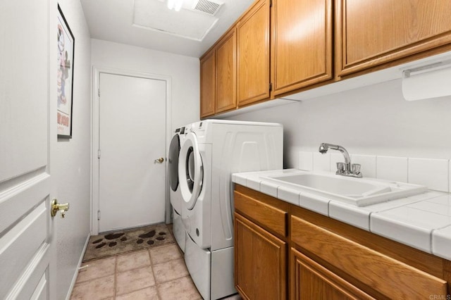 clothes washing area featuring a sink, cabinet space, washing machine and clothes dryer, and visible vents