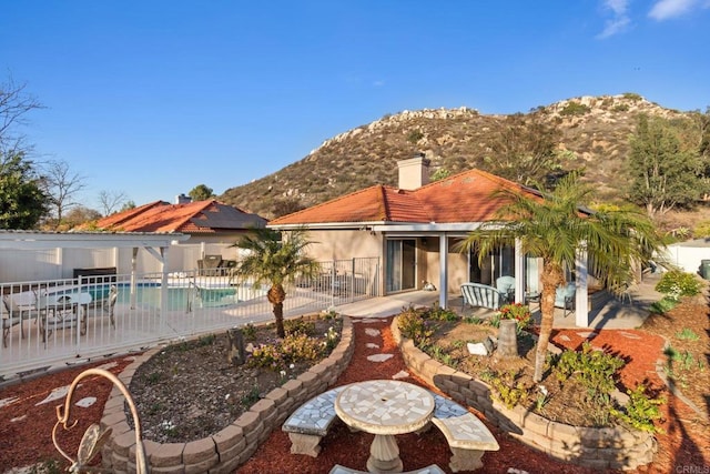 back of property featuring a patio area, a mountain view, a chimney, and stucco siding