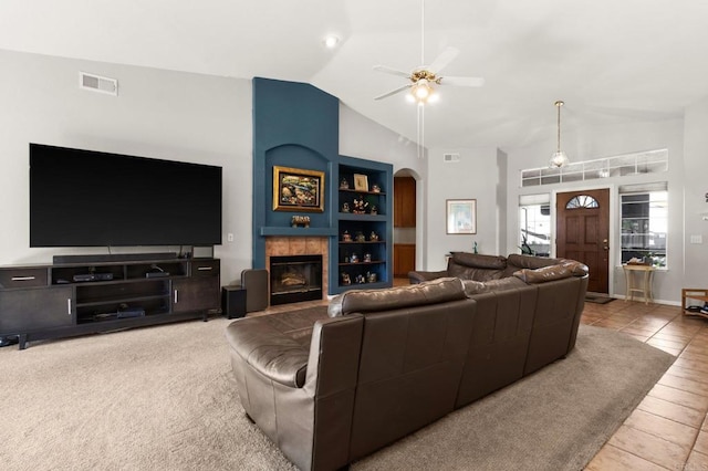 living area featuring a tiled fireplace, visible vents, arched walkways, and built in features