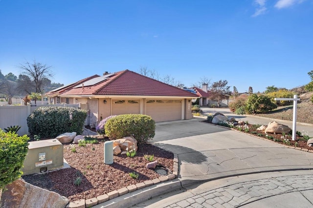 view of front of home featuring a garage, concrete driveway, a tile roof, roof mounted solar panels, and stucco siding