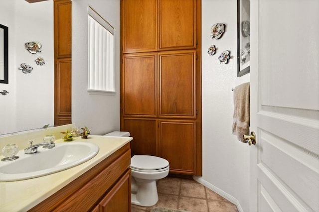 bathroom with toilet, baseboards, vanity, and tile patterned floors