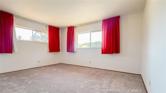 spare room featuring carpet floors and baseboards