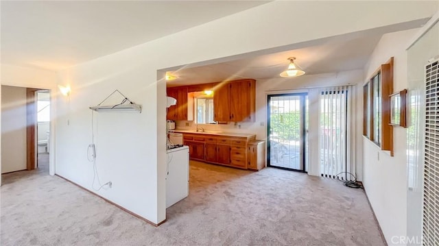 kitchen with brown cabinets, light countertops, washer / clothes dryer, and light carpet