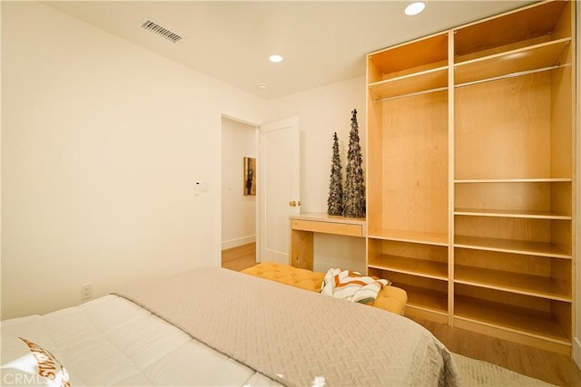 bedroom with a closet, visible vents, recessed lighting, and wood finished floors