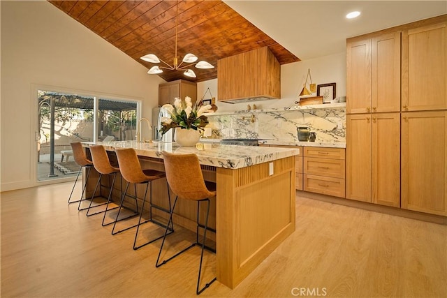 kitchen featuring backsplash, a kitchen island with sink, wooden ceiling, and light wood finished floors