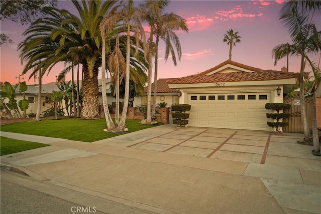 mediterranean / spanish-style home featuring stucco siding, a tile roof, a yard, concrete driveway, and an attached garage