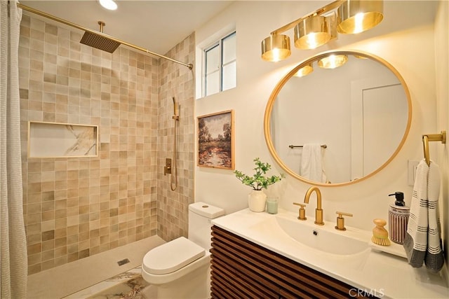 bathroom featuring tiled shower, toilet, and vanity