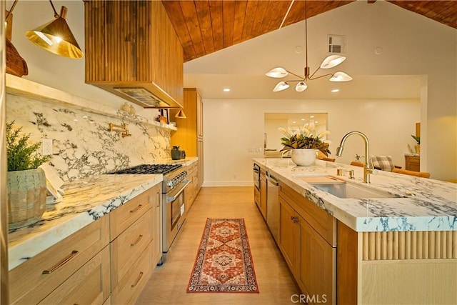 kitchen with a sink, light stone counters, stainless steel appliances, a chandelier, and vaulted ceiling