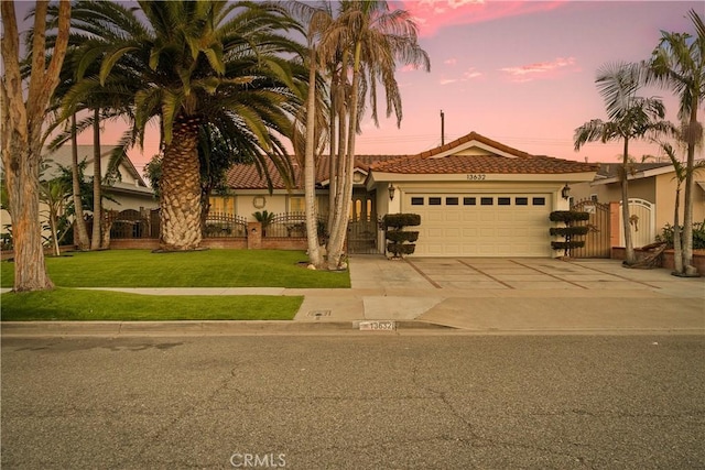 mediterranean / spanish-style house with a front lawn, fence, concrete driveway, stucco siding, and a garage