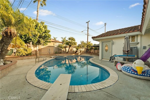 view of swimming pool featuring a diving board, a patio, a fenced backyard, and a pool with connected hot tub