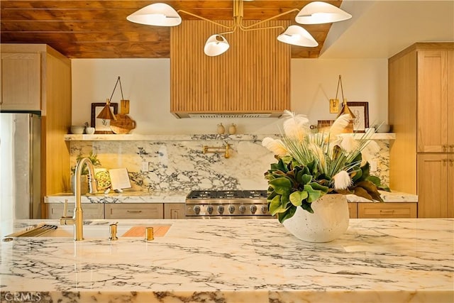 kitchen featuring light stone counters, freestanding refrigerator, a sink, range, and backsplash