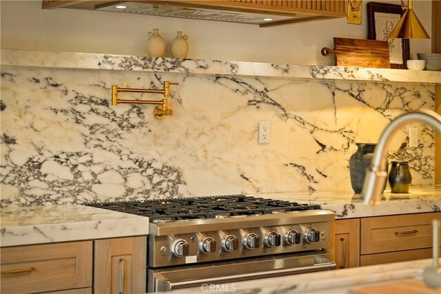 kitchen with light stone counters, high end stainless steel range oven, and decorative backsplash