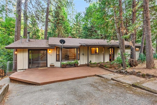 back of property featuring a chimney, a wooden deck, and fence