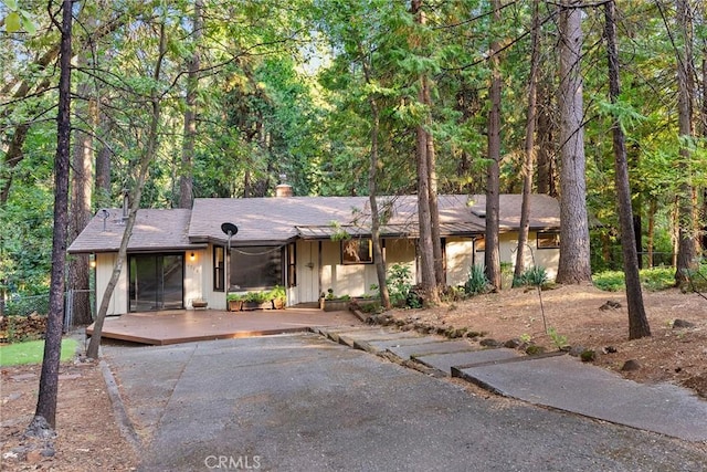 view of front of property featuring fence, a deck, and a wooded view