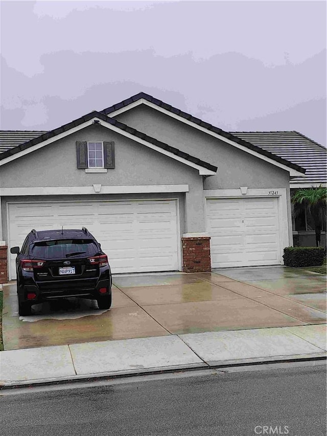 ranch-style house with concrete driveway, brick siding, an attached garage, and stucco siding